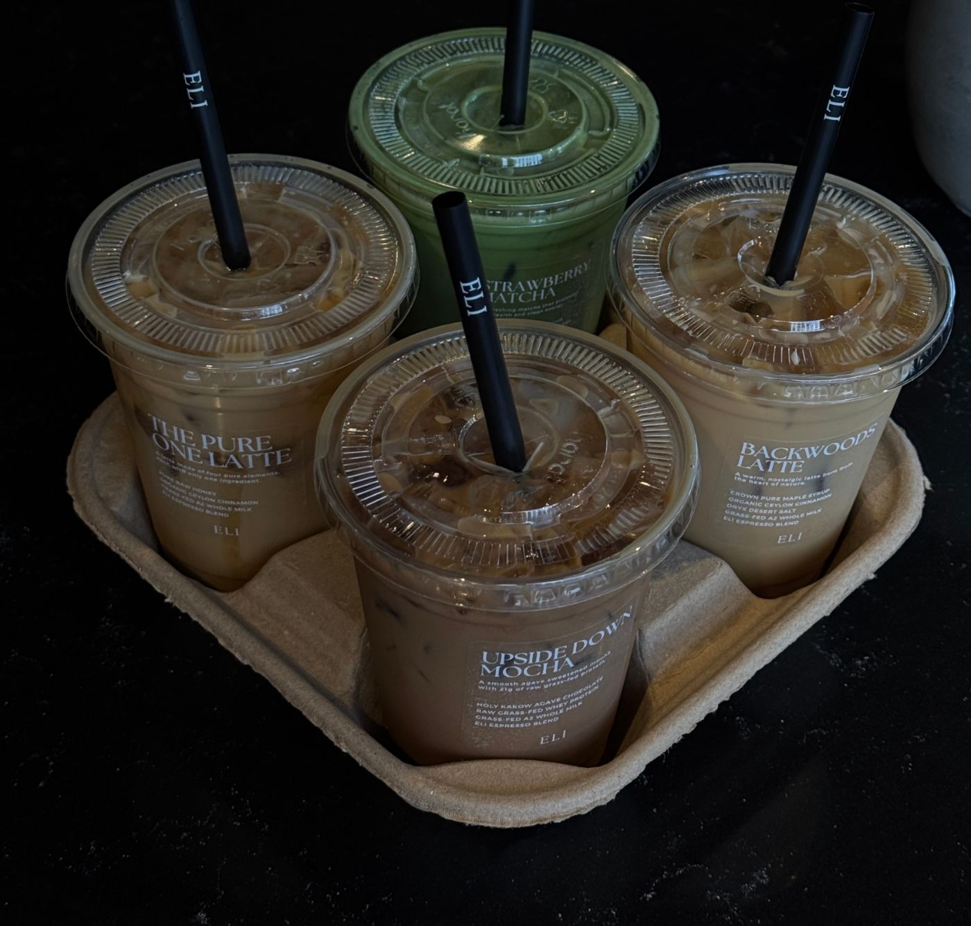 Four ELI drinks in a paper carrier on the counter, names written on the cups
