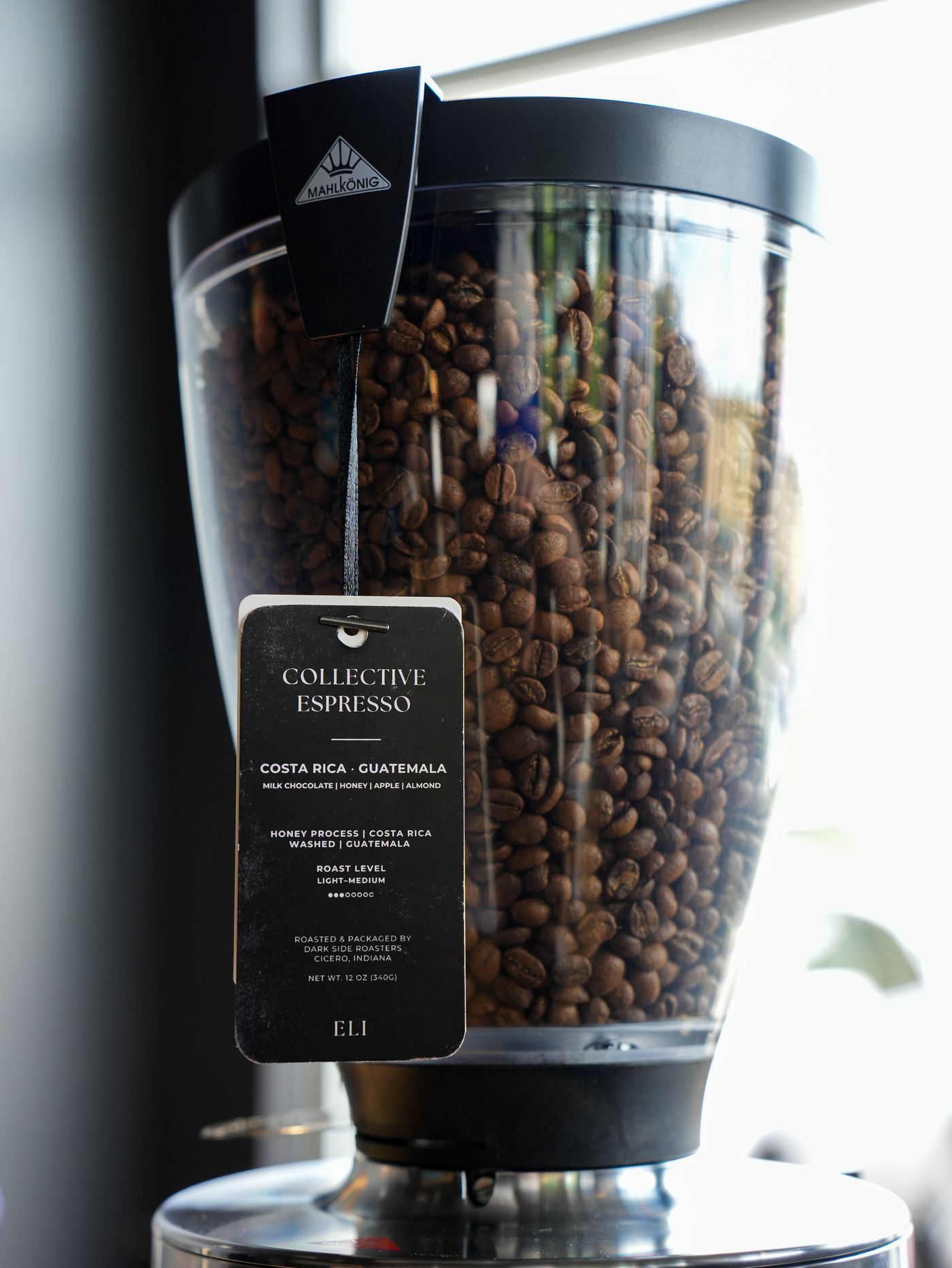 The Collective Espresso tag hanging from the bar's Mahlkönig grinder, full of beans
