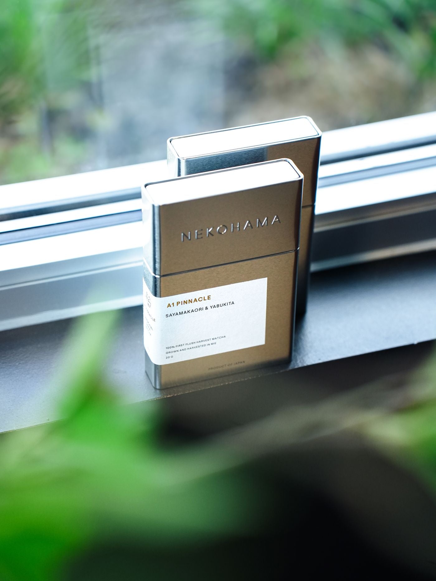 Two silver Nekohama A1 Pinnacle matcha tins on a windowsill